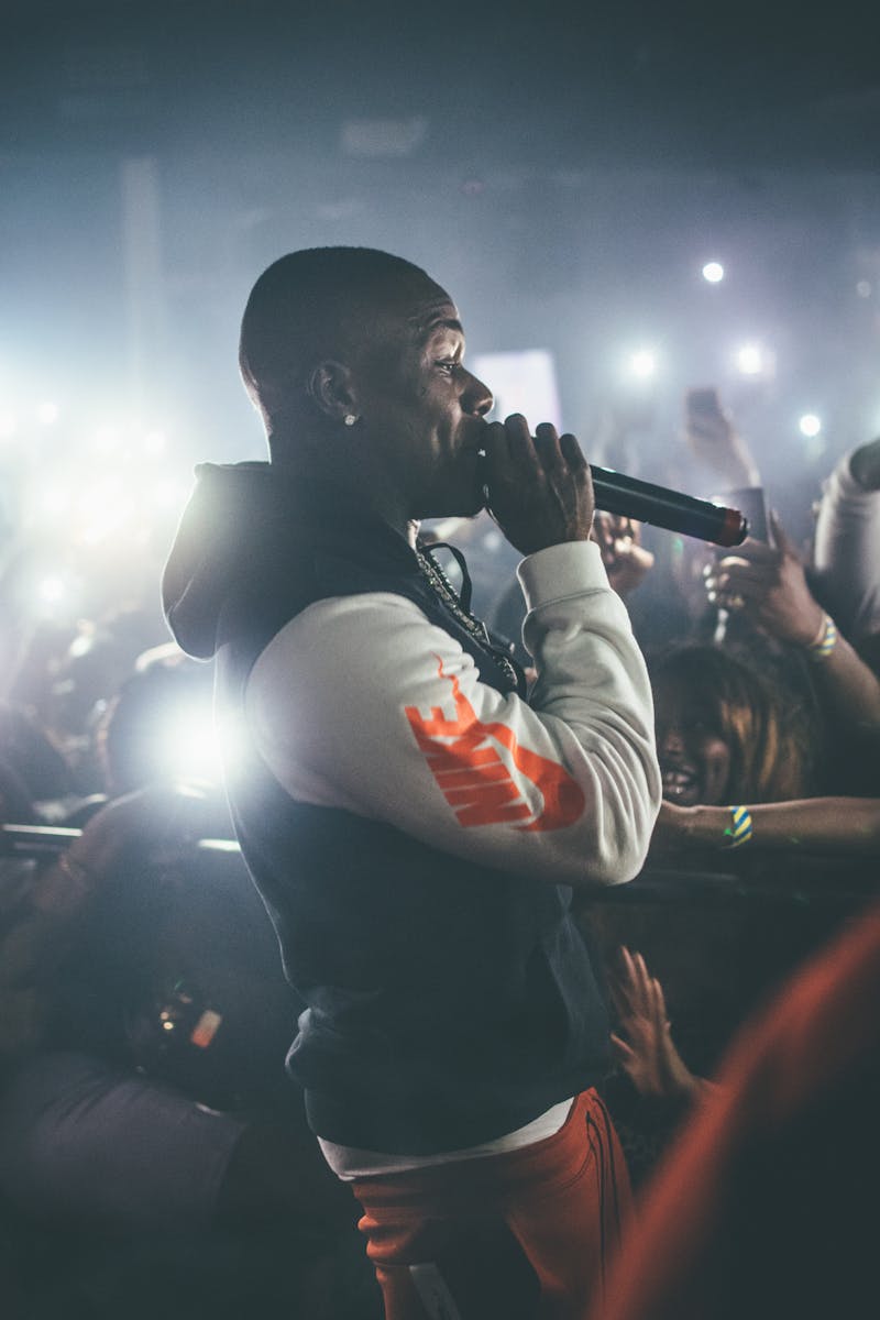 Dynamic shot of a rapper performing live in a crowded nightclub with vibrant lights.